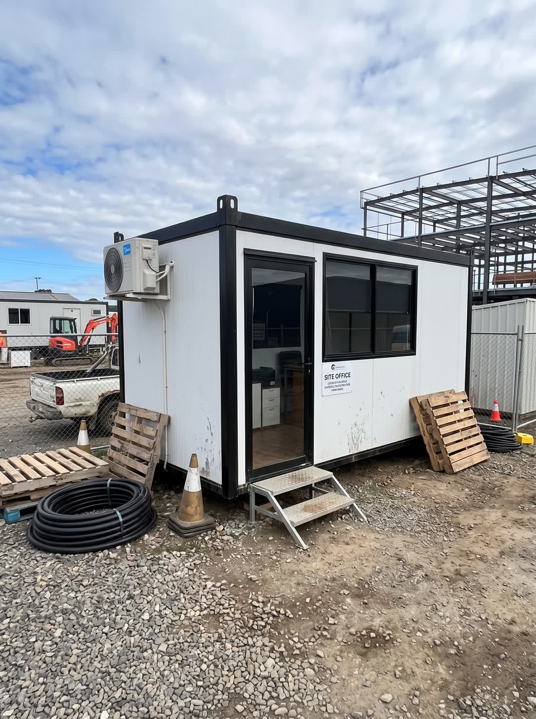 Container escritório instalado em frente a uma obra de estrutura metálica